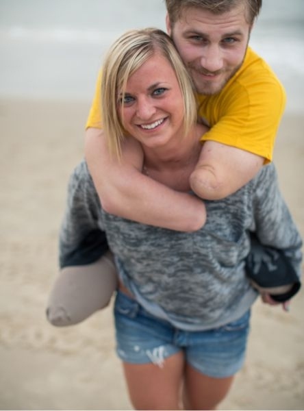 Taylor Morris riding piggyback on his girlfriend along the beach, both of them laughing