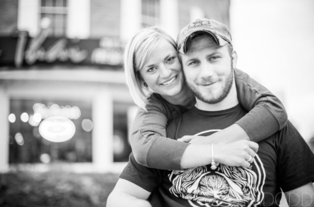 Black and white portrait of Taylor Morris with his girlfriend hugging him from behind