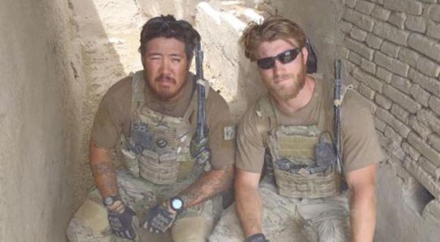 Taylor Morris and a teammate resting against a mud wall between patrols in Afghanistan
