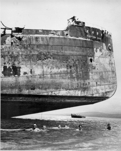 US Coast Guard crewmen swim under Japanese Kinugawa Maru beached in Solomon Islands November 1943