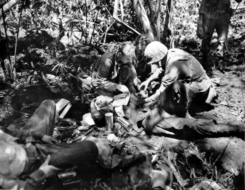 Wounded Marine receives treatment from Navy corpsman at first aid station on New Britain February 1944
