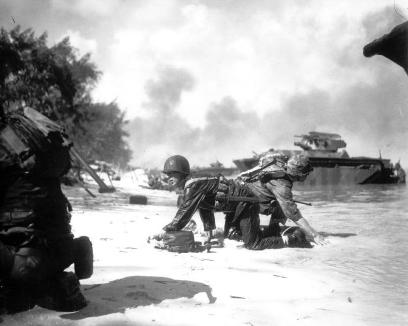 Two US Marines crawl to positions under enemy fire on beach at Saipan June 1944