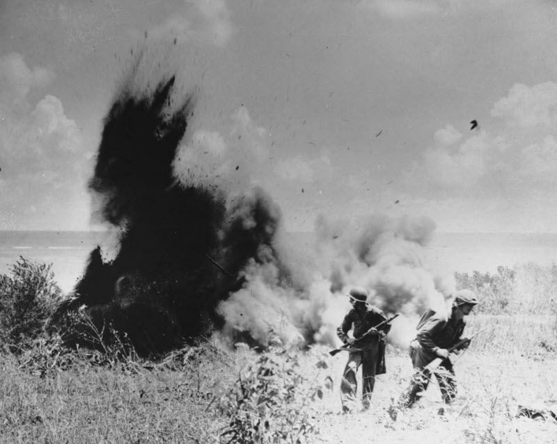 US Marines walk away after blowing up Japanese foxhole during invasion at Saipan July 1944
